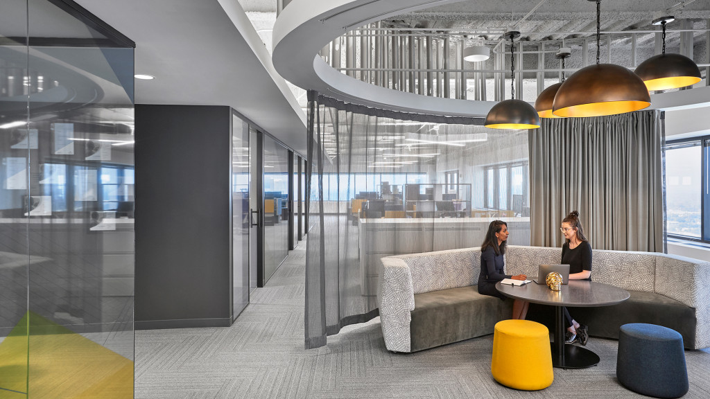 A couple of women sitting at a table in a room with a large glass wall and a large.